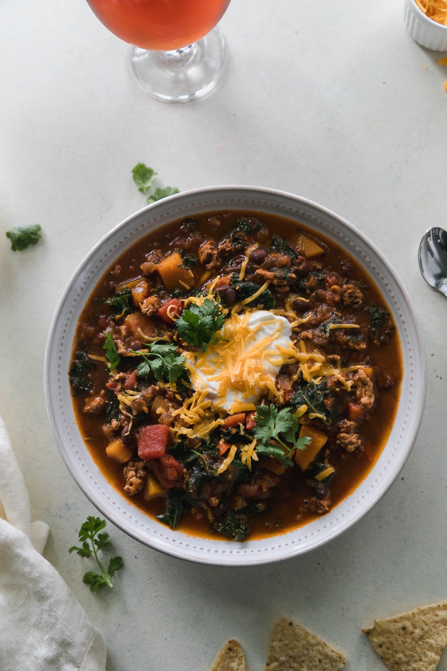 Overhead shot of a bowl of chili topped with sour cream, shredded cheddar, and cilantro