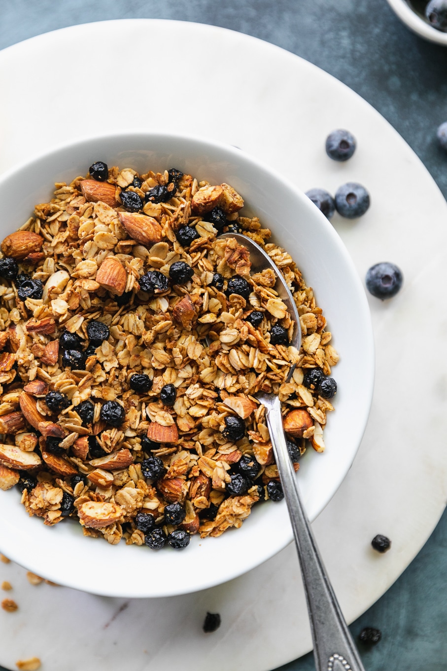 Overhead close up shot of a bowl of lemon blueberry granola with a spoon in the bowl