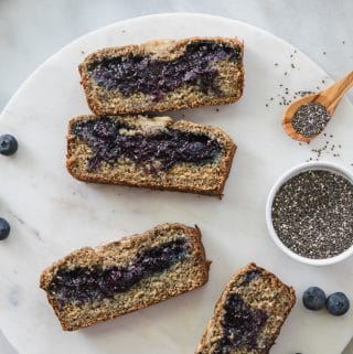 Overhead shot of slices of blueberry chia jam stuffed banana bread on a circular marble board
