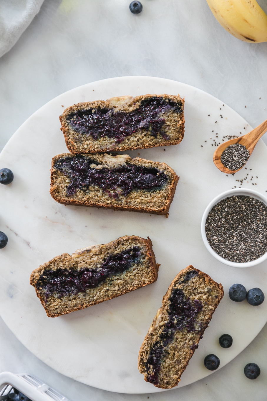 Overhead shot of slices of blueberry chia jam stuffed banana bread on a circular marble board