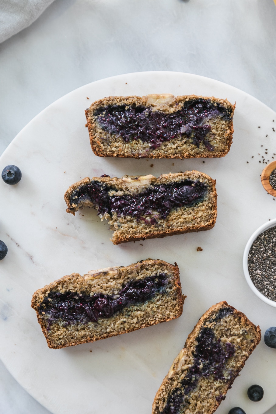 Overhead shot of slices of blueberry chia jam stuffed banana bread with a bite taken out of one of the slices