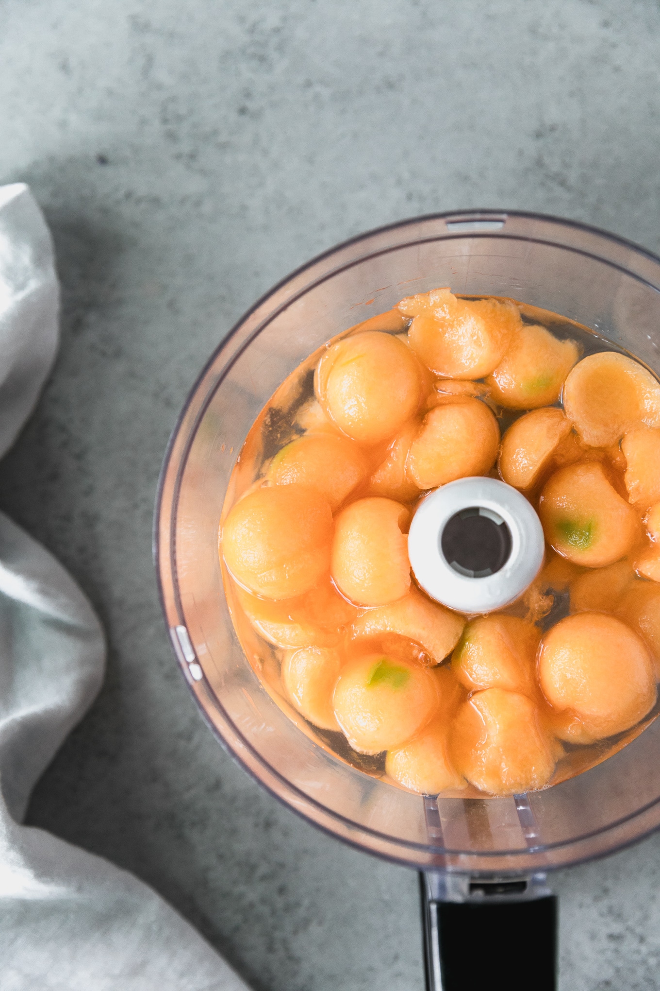 Overhead shot of a food processor filled with melon balls and simple syrup