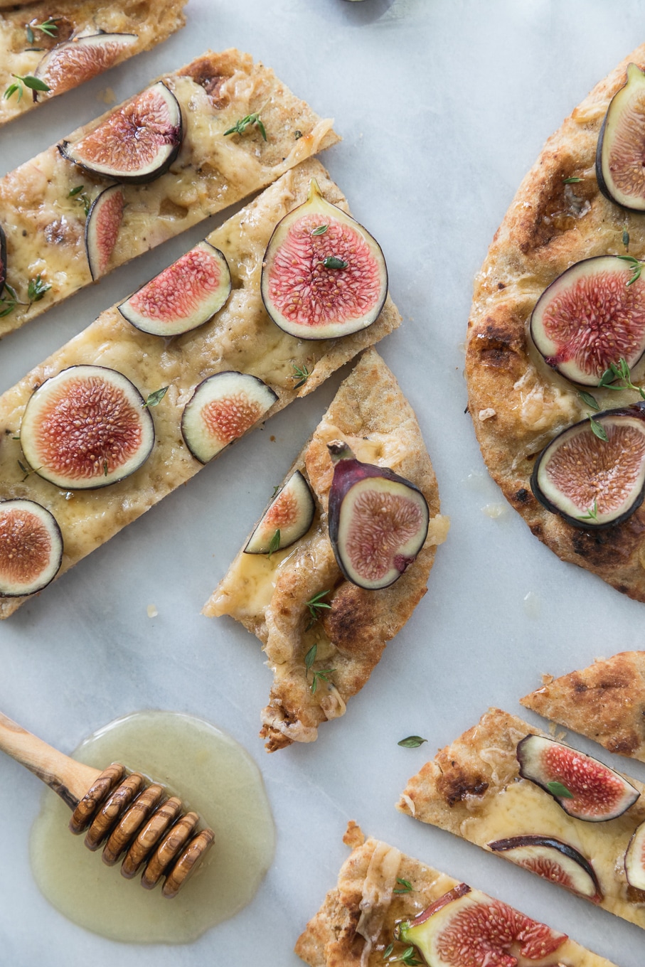 Overhead close up shot of a fig flatbread sliced into pieces with a bite taken out of one piece