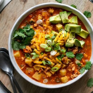 Overhead shot of a bowl of chili topped with cheese, cilantro, and avocado