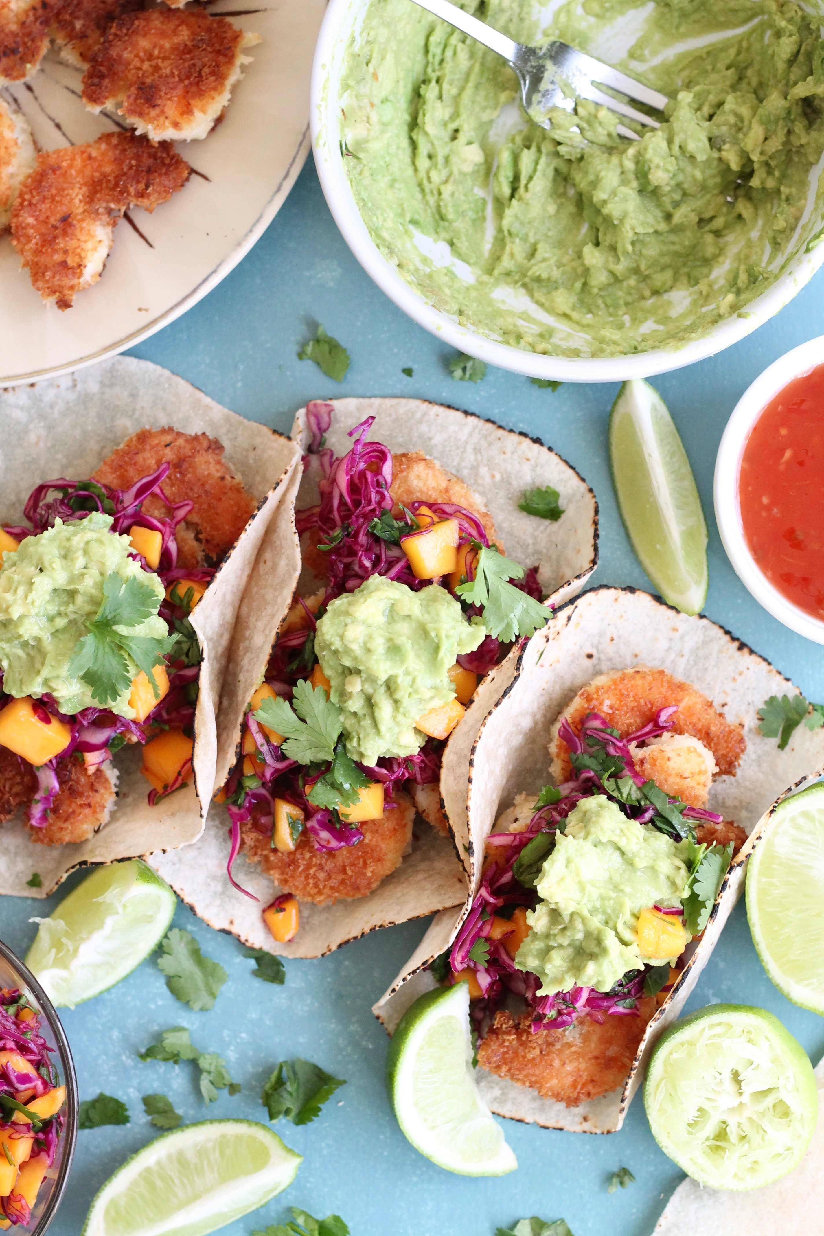 Overhead shot of shrimp tacos topped with mango slaw and avocado mash