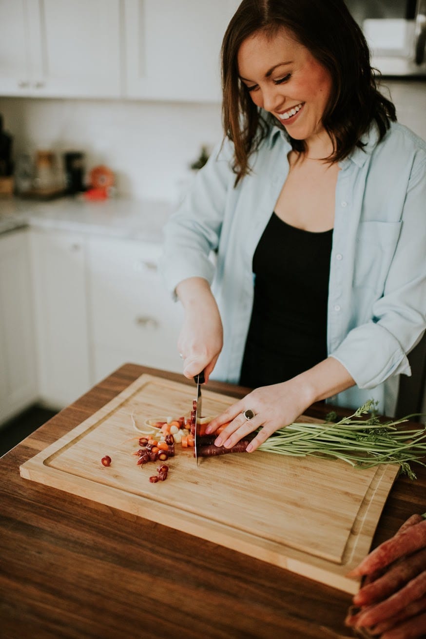Woman smiling and chopping rainbow carrots