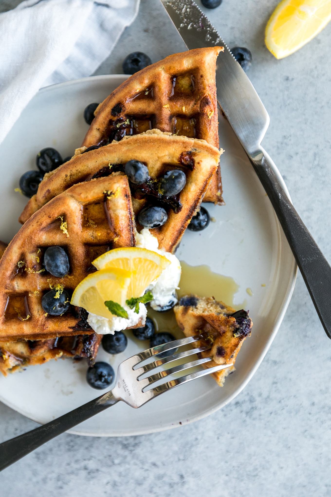 Overhead close up shot of a plate of waffles being cut into with a fork