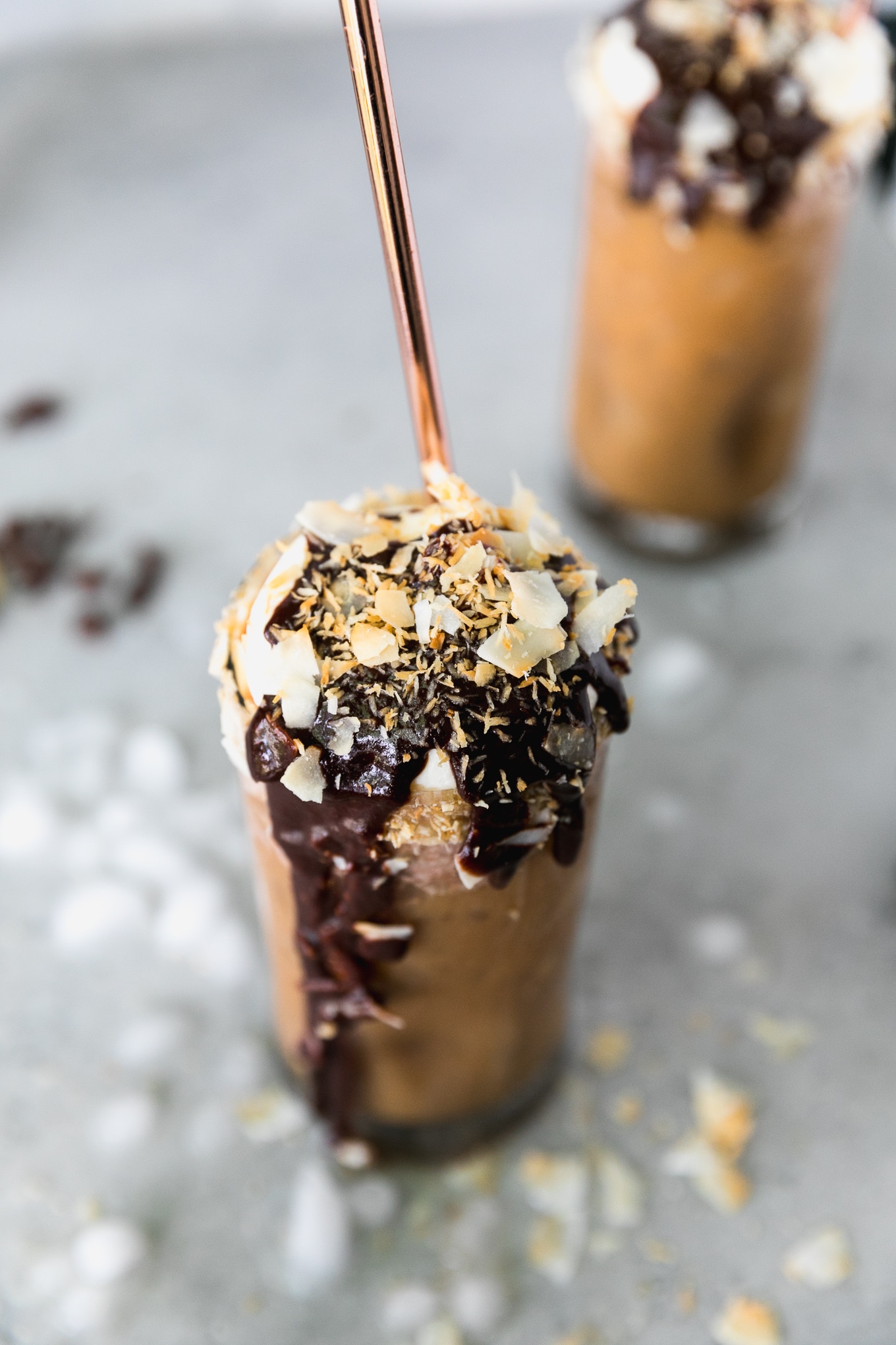 Close up shot of an iced coffee with lots of chocolate sauce dripping down the glass and lots of toasted coconut on top