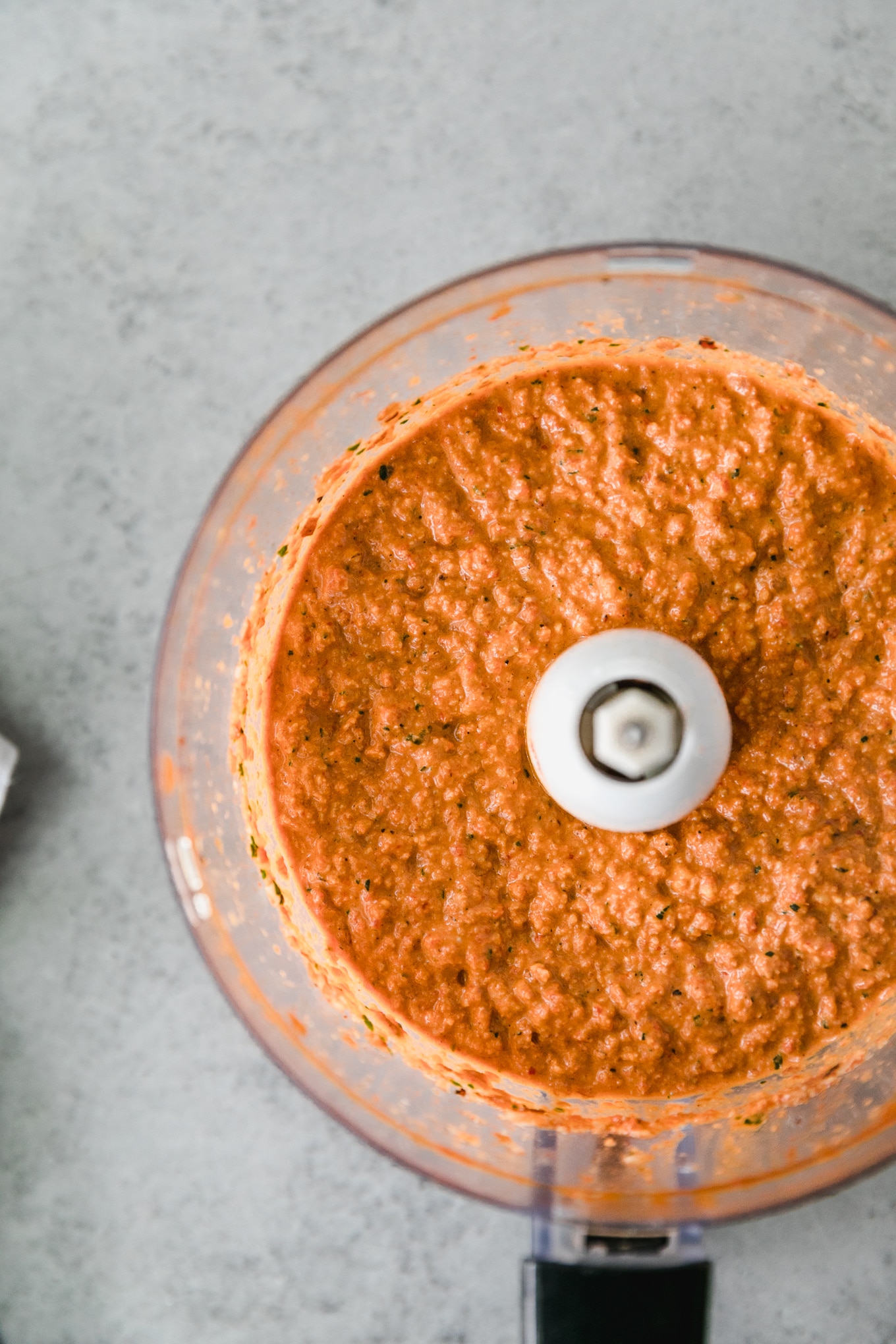 Overhead shot of a food processor filled with bright orange romesco sauce