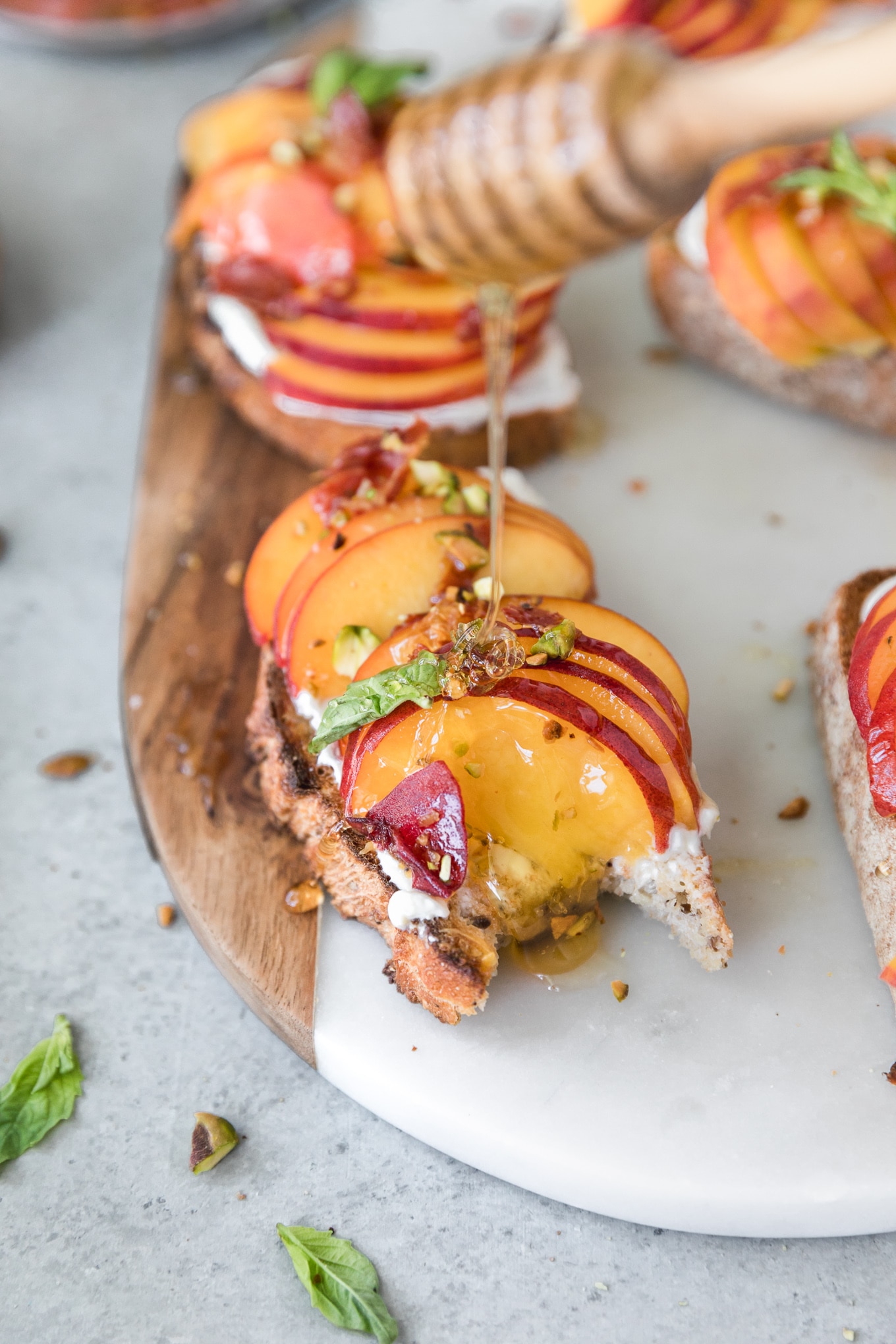 Close up shot of a piece of peach toast with a bite taken out of it and honey being drizzled on top