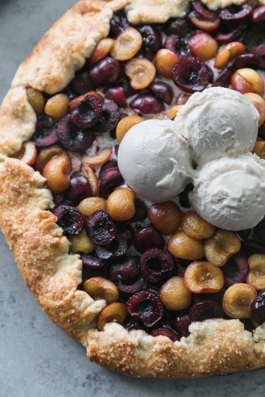 Overhead close up shot of a cherry galette with 3 scoops of ice cream on top