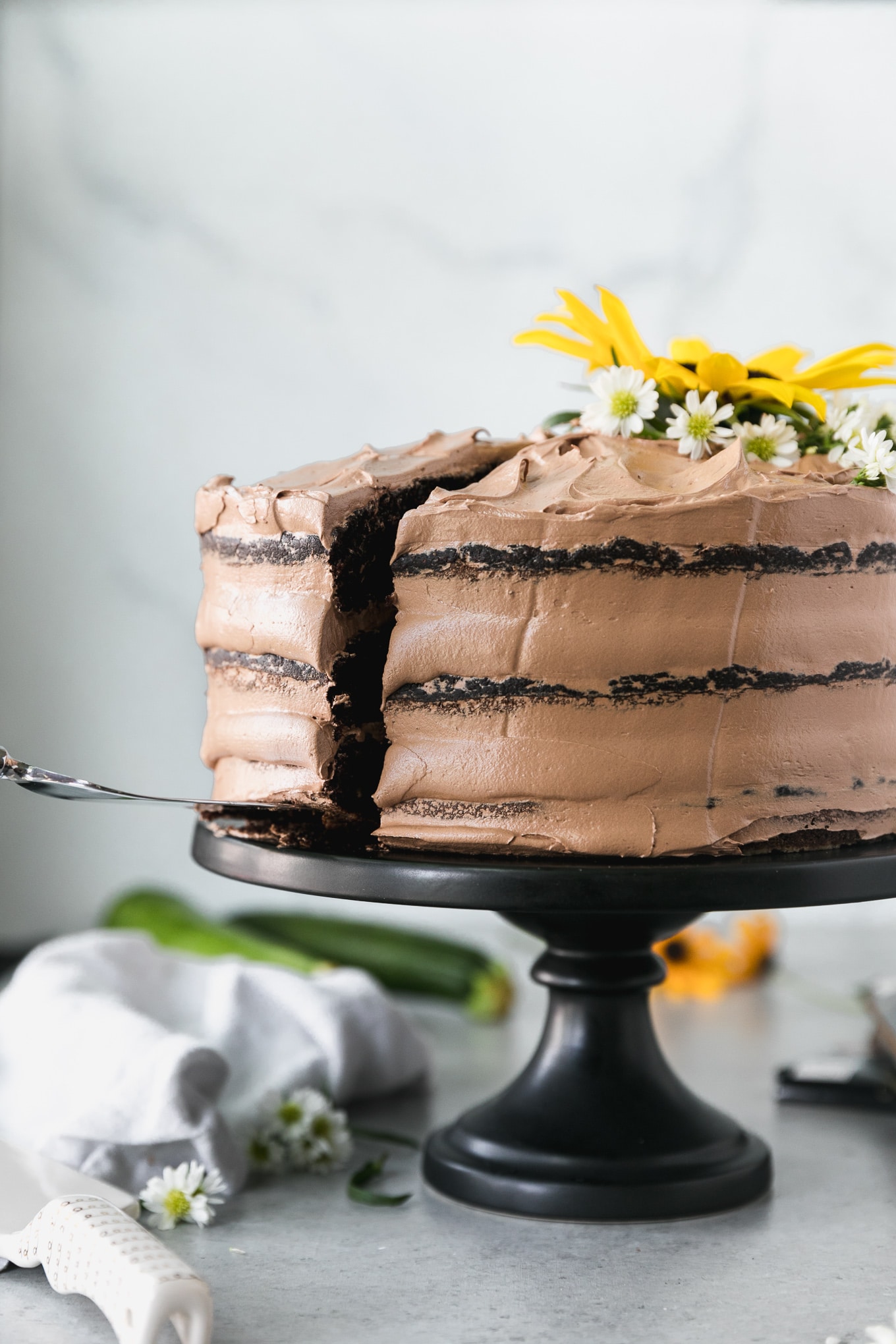 Forward facing shot of a chocolate cake with a slice being pulled out from the left side