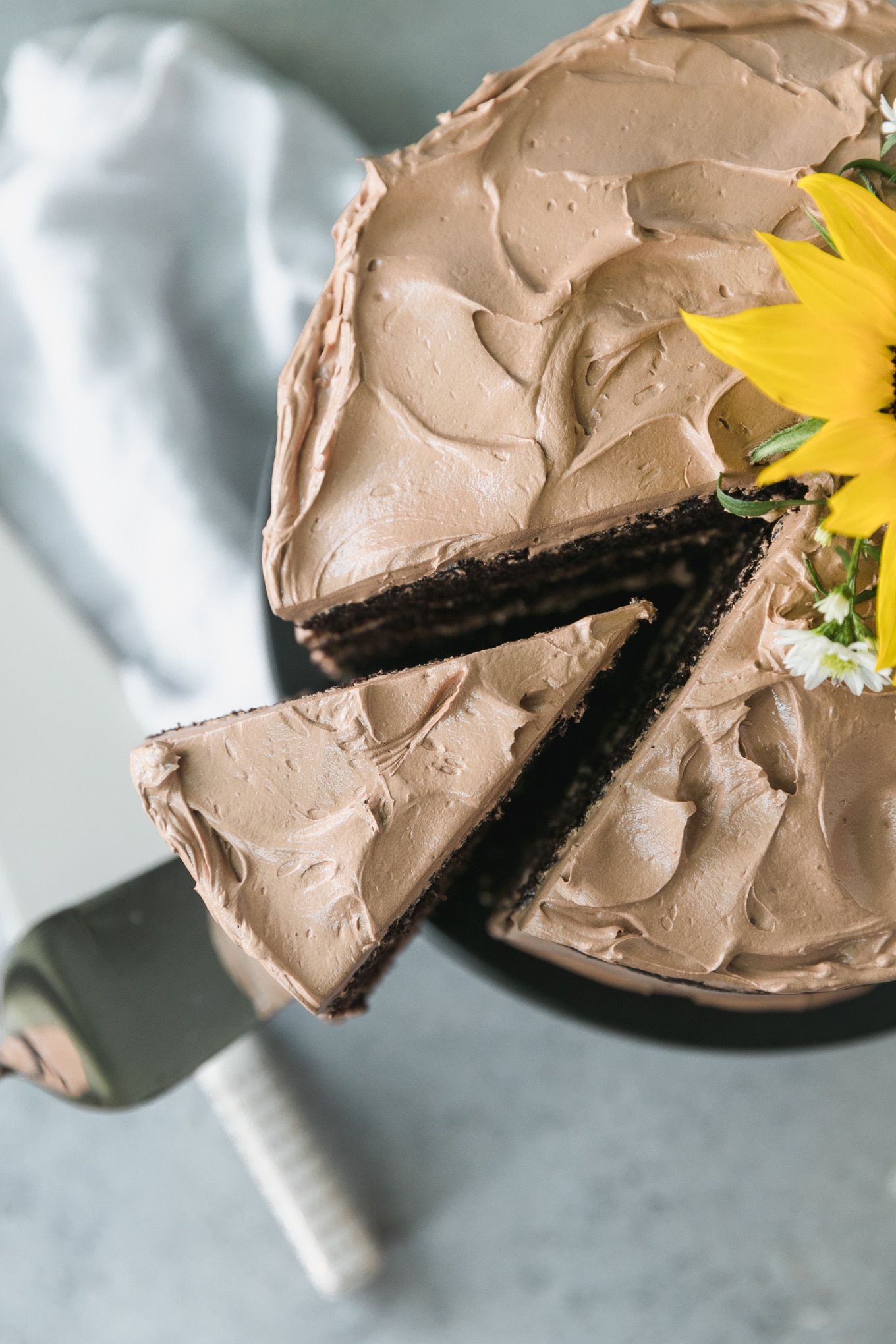 Overhead close up shot of a piece of chocolate cake being taken out from the cake