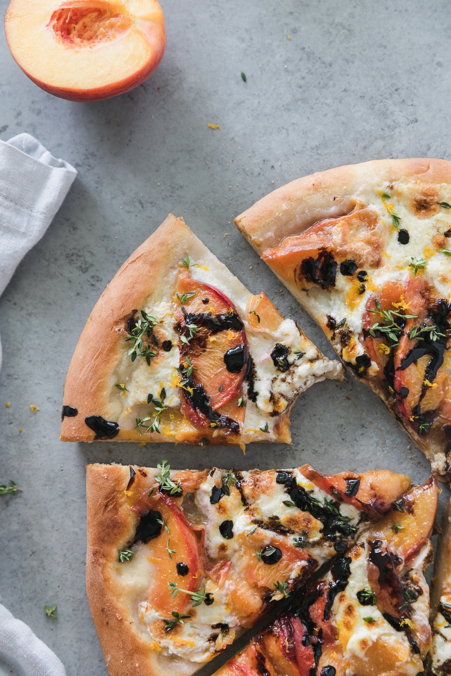 Overhead shot of a slice of peach pizza with a bite taken out of it