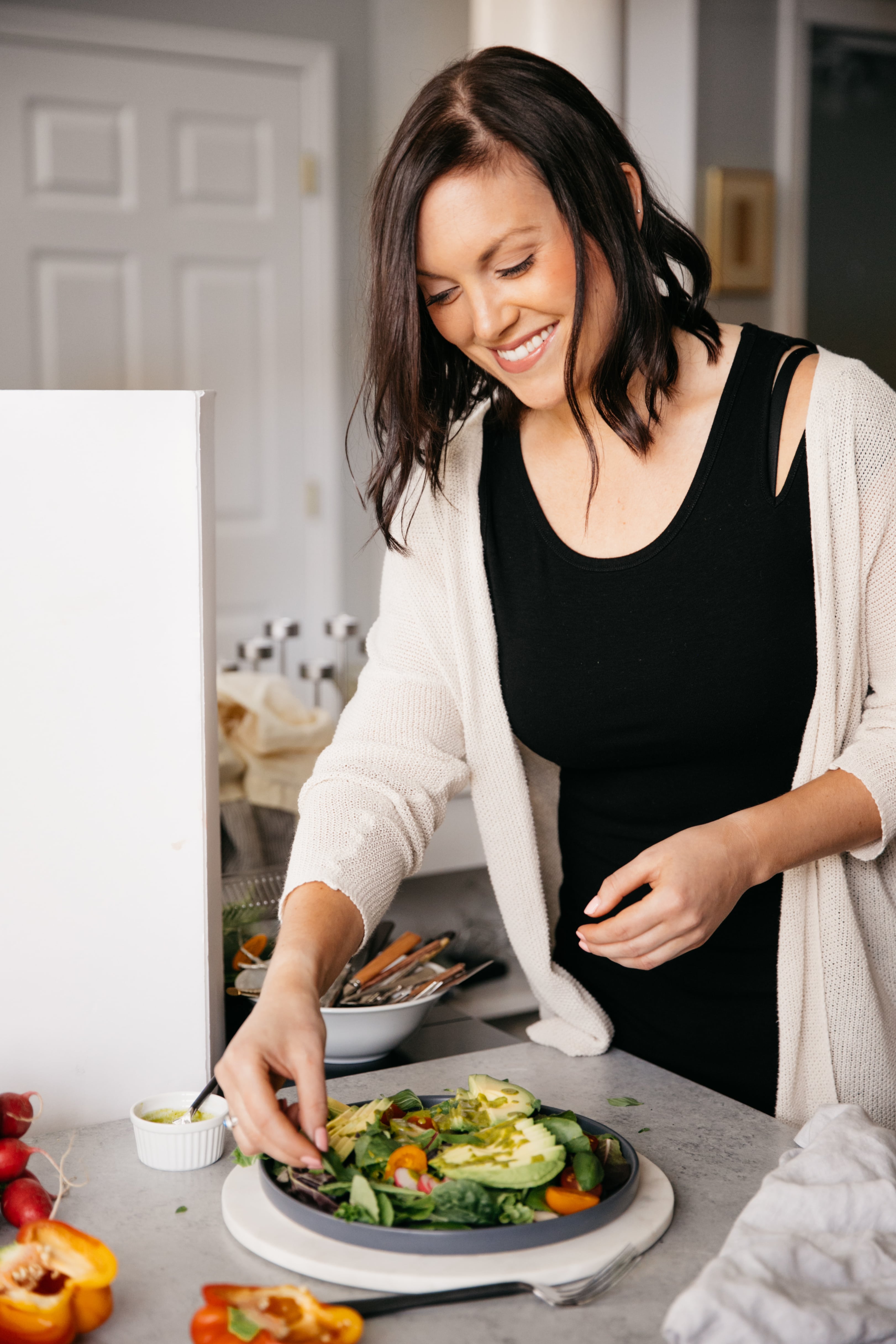 Photo of woman smiling and styling a colorful salad