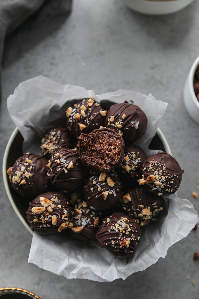 Overhead shot of a bowl of dark chocolate nutella truffles with a bite taken out of the one on top