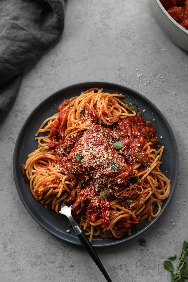 Overhead shot of a plate of chicken cacciatore over pasta with a fork twirling noodles resting on the plate