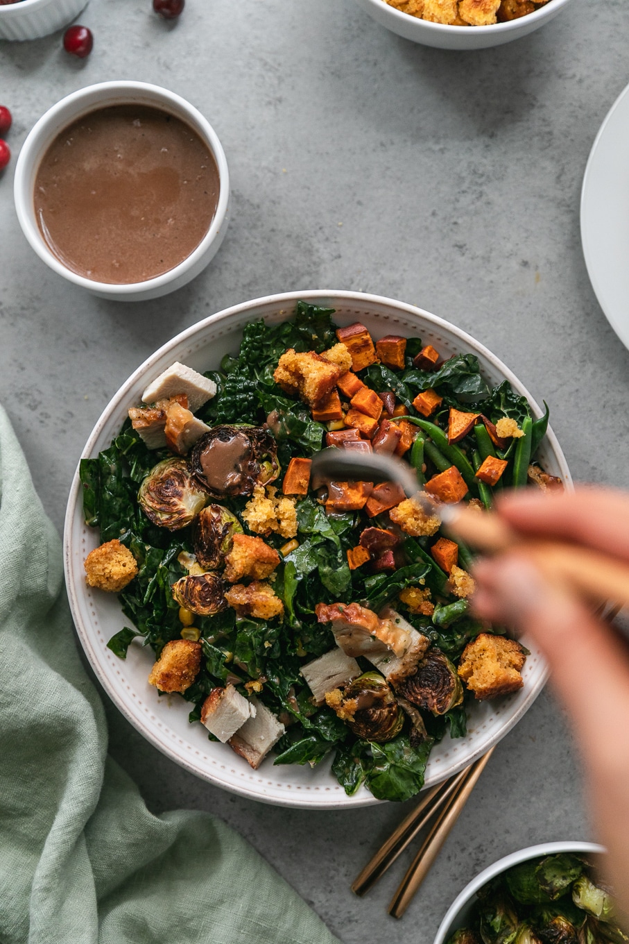 Overhead shot of a thanksgiving leftovers kale salad bring drizzled with cranberry balsamic vinaigrette
