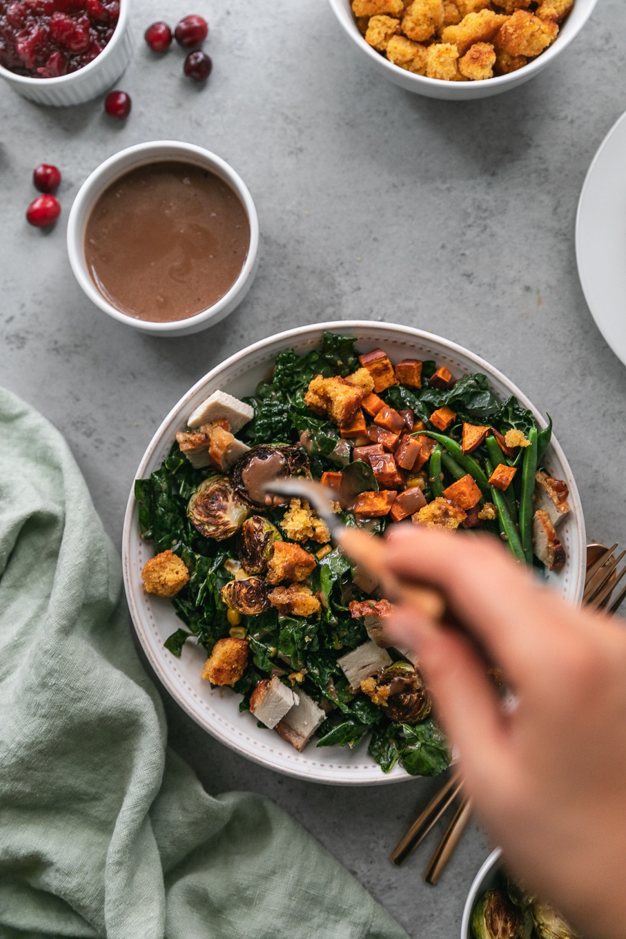Overhead shot of a thanksgiving leftovers kale salad bring drizzled with cranberry balsamic vinaigrette