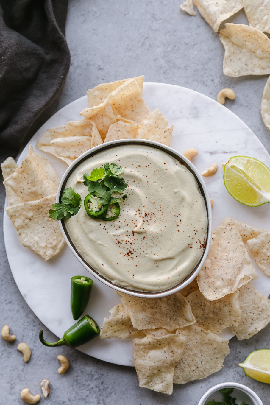 Overhead shot of a bowl of queso and a hand dipping a chip in it and chips scattered around the bowl