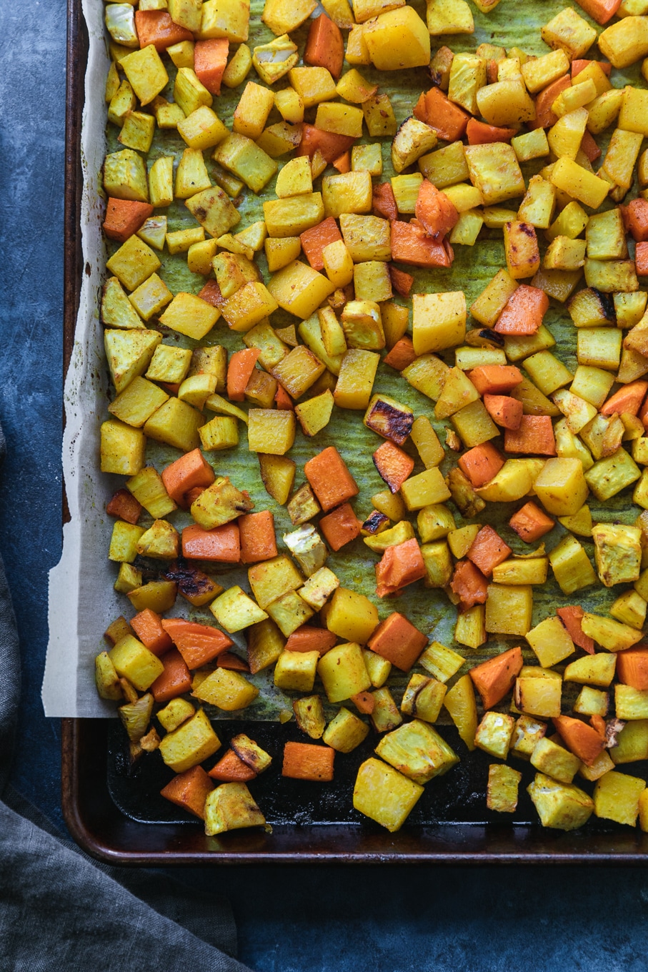 Overhead shot of a sheet pan filled with roasted yellow and orange root vegetables