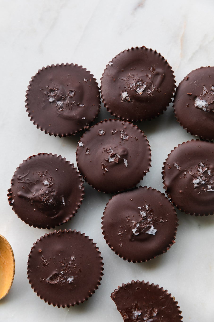 Overhead shot of mini dark chocolate tahini cups with a spoonful of tahini next to them