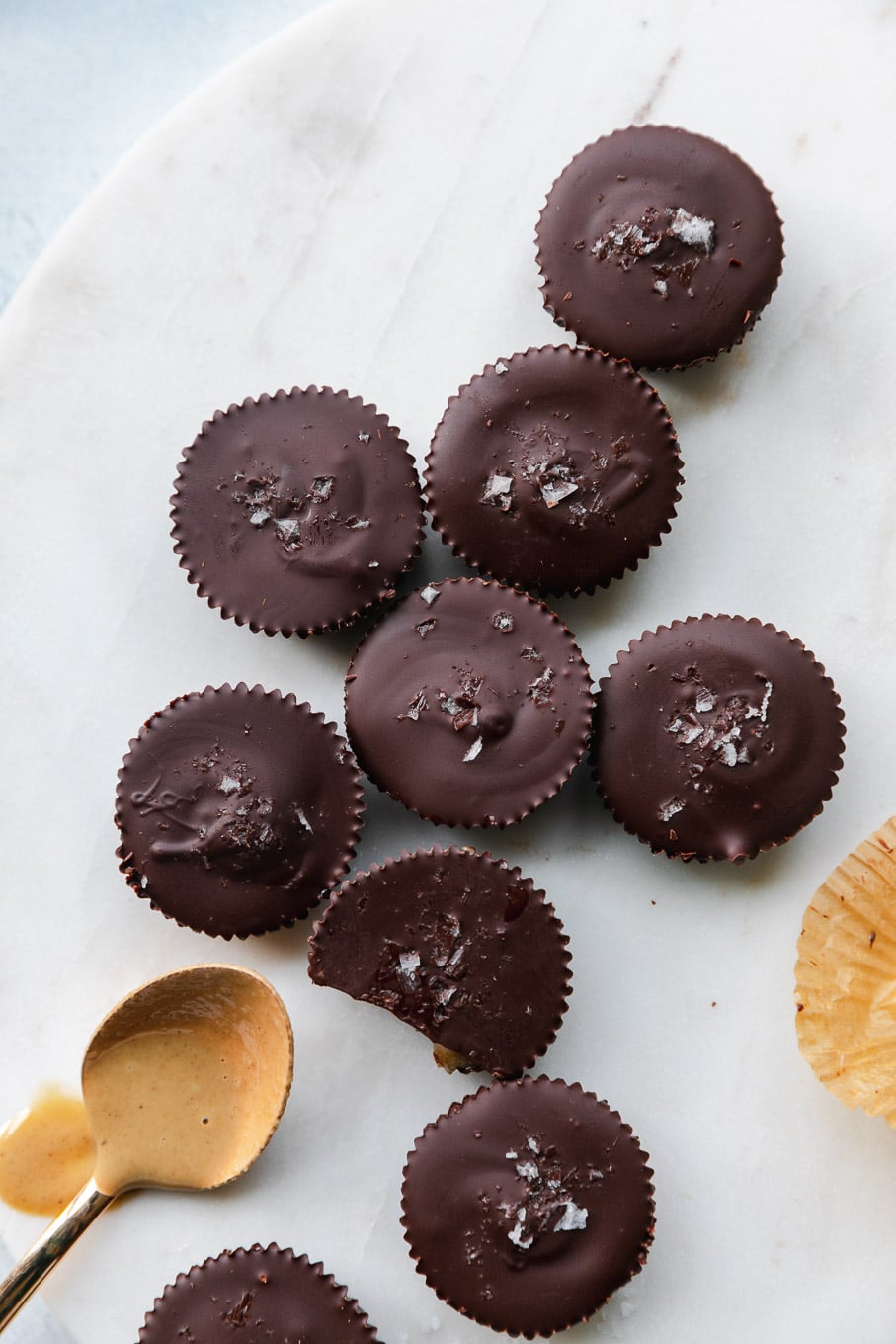 Overhead shot of mini dark chocolate tahini cups with a spoonful of tahini next to them