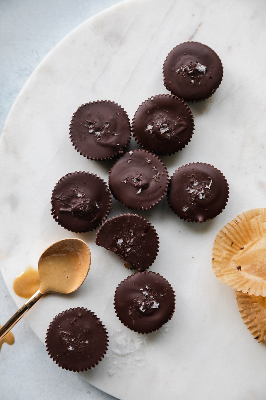 Overhead shot of mini dark chocolate tahini cups with a spoonful of tahini next to them