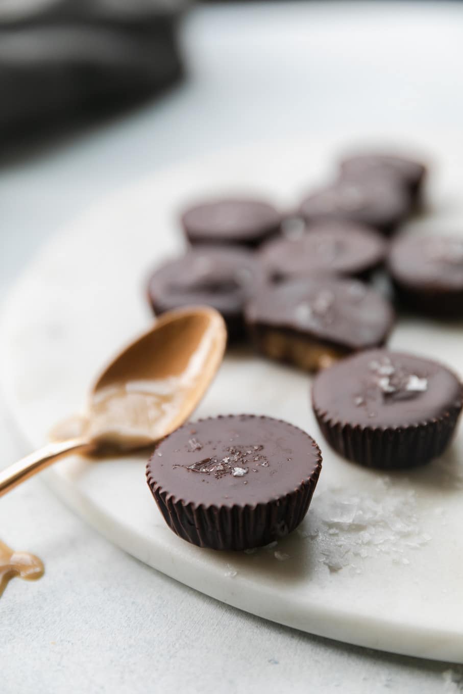 Close up shot of mini dark chocolate tahini cups with a spoonful of tahini next to it