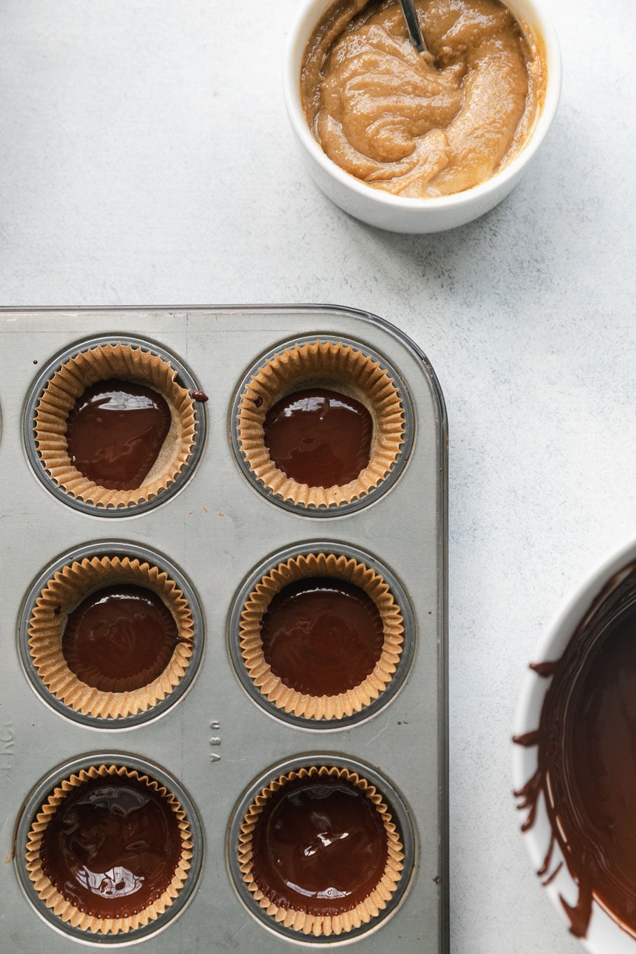 Overhead shot of mini muffin tins filled with spoonfuls of melted dark chocolate