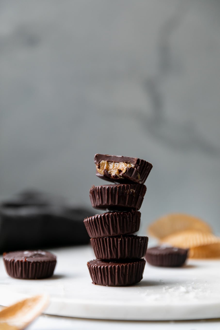 Forward facing shot of a stack of dark chocolate tahini cups with a bite taken out of the one on top
