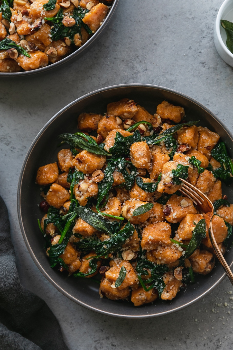 Overhead shot of a bowl of sweet potato gnocchi with spinach and toasted hazelnuts