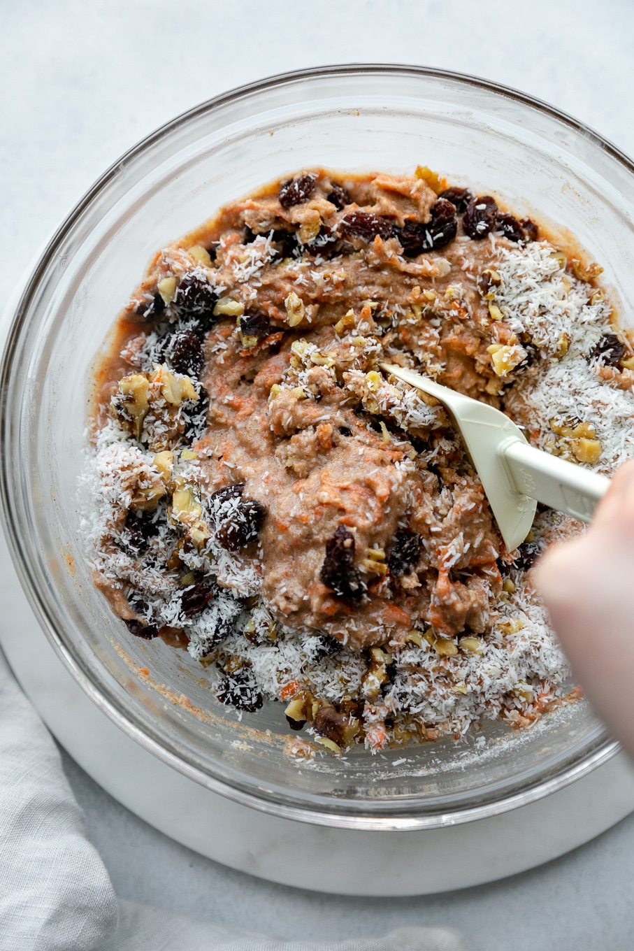 Overhead shot of carrot cake muffin batter in a bowl being stirred with a rubber spatula