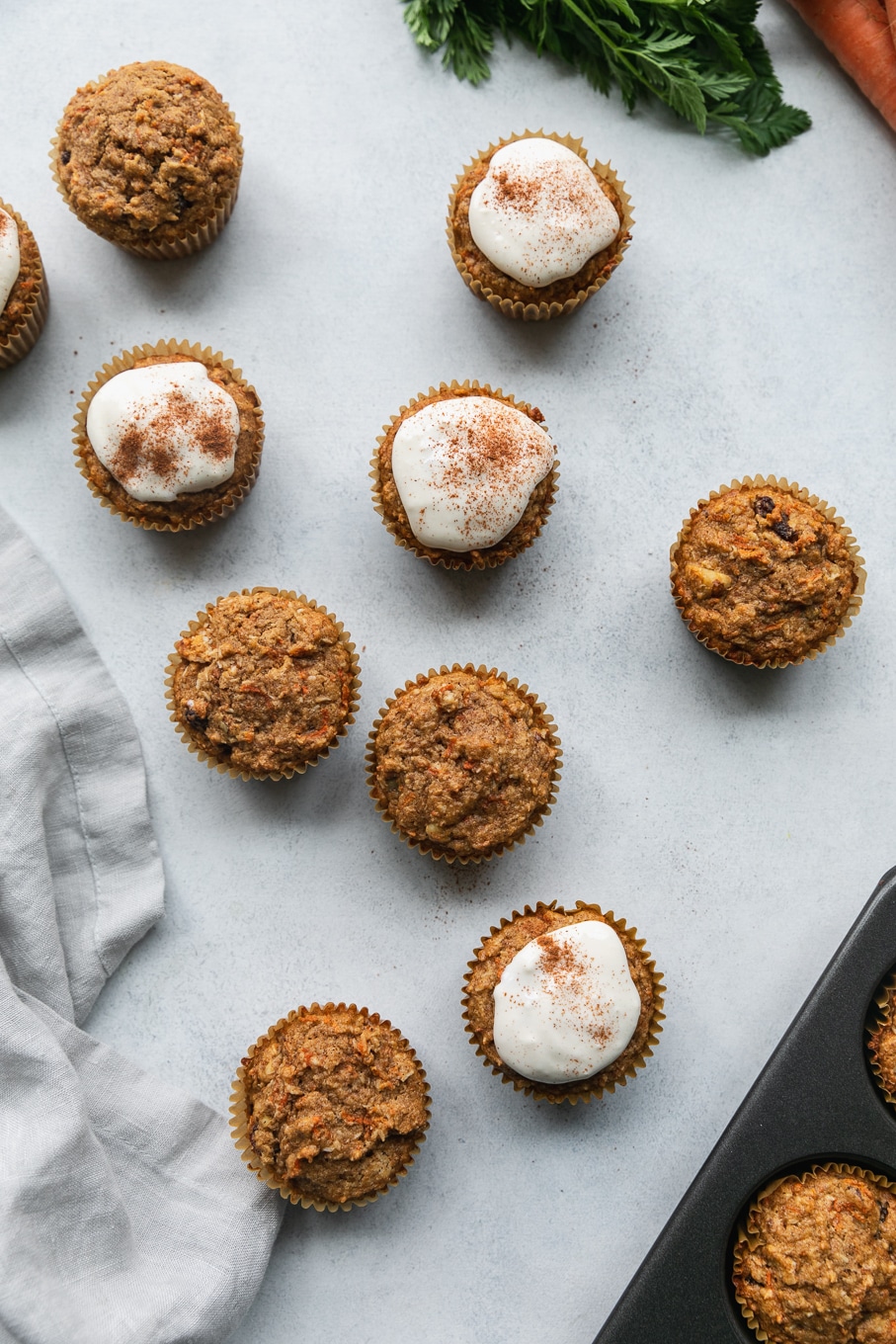 Overhead shot of carrot cake muffins with some with cream cheese glaze on them