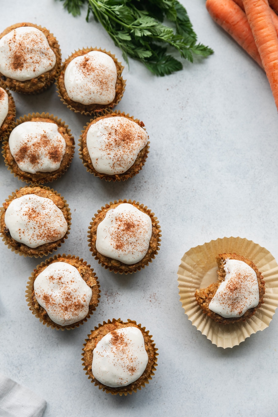 Overhead shot of cream cheese glazed carrot cake muffins with one with a bite taken out