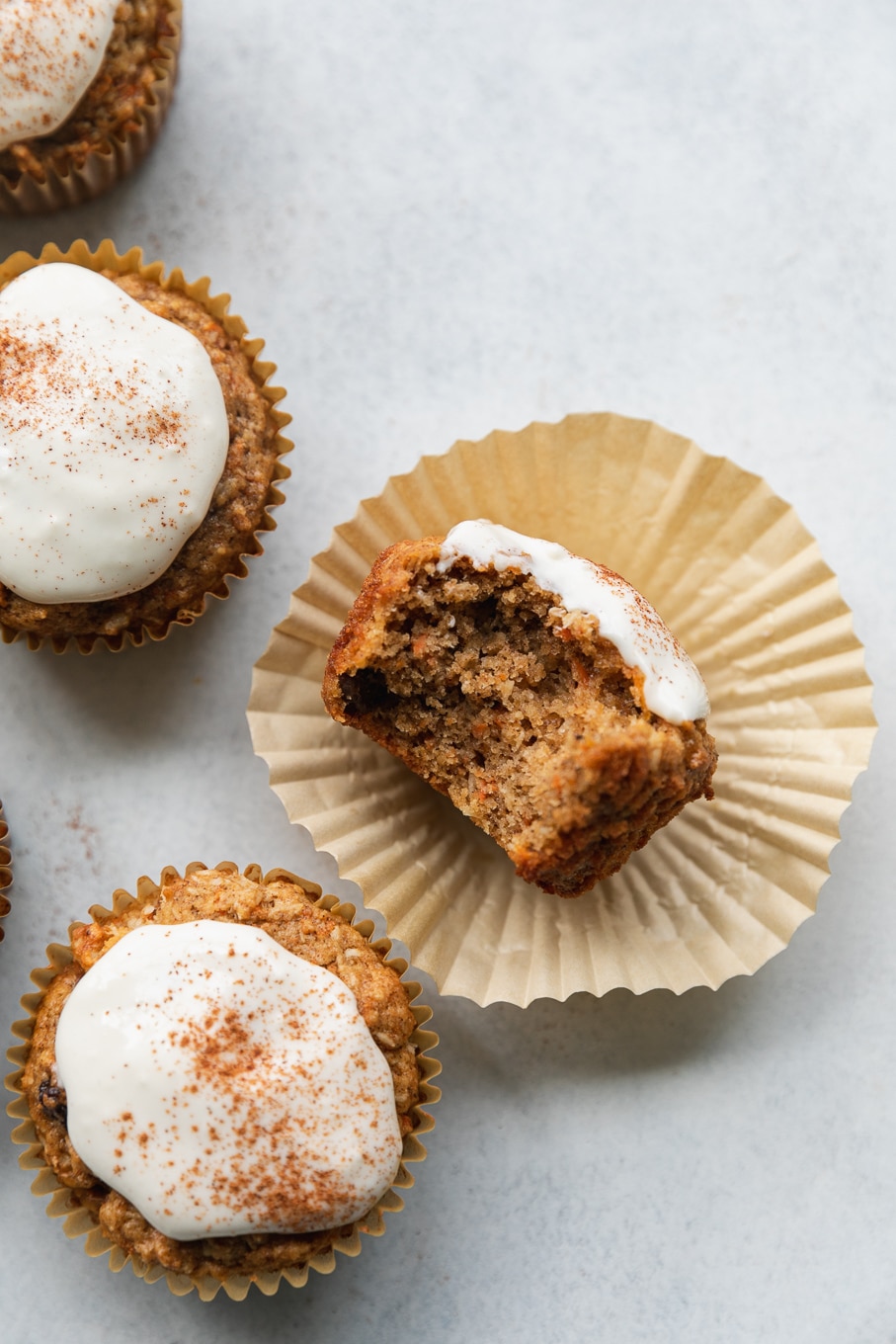 Overhead close up shot of a carrot cake muffin with cream cheese glaze with a bite taken out