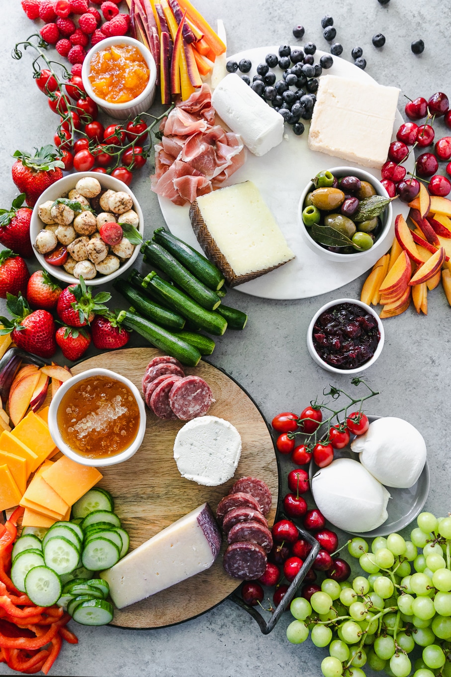 Overhead shot of cheeses, salami, fruit, and vegetables