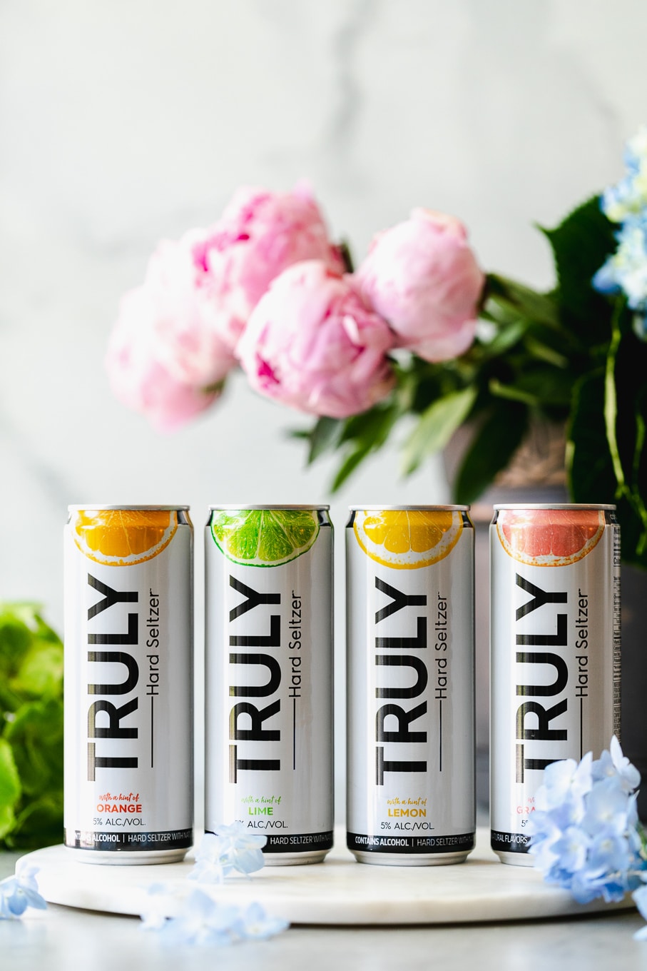 Shot of 4 cans of hard seltzer with flowers in the background