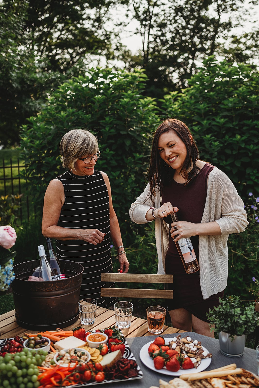 Shot of two women smiling and opening a bottle of wine