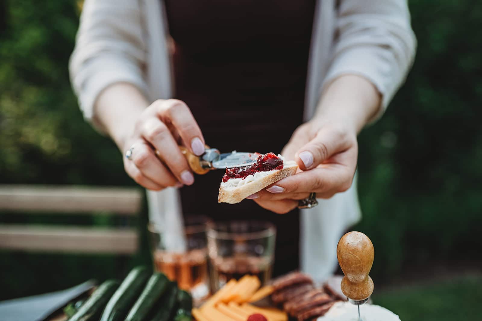Close up shot of someone spreading cherry preserves on a baguette