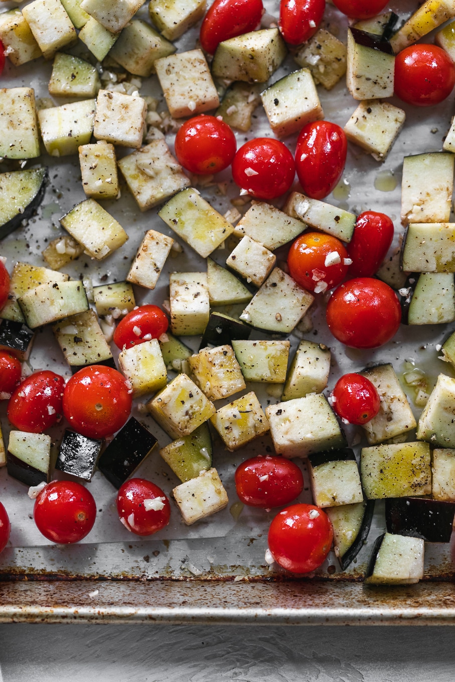 Overhead close up shot of a sheet pan filled with tomatoes and eggplant