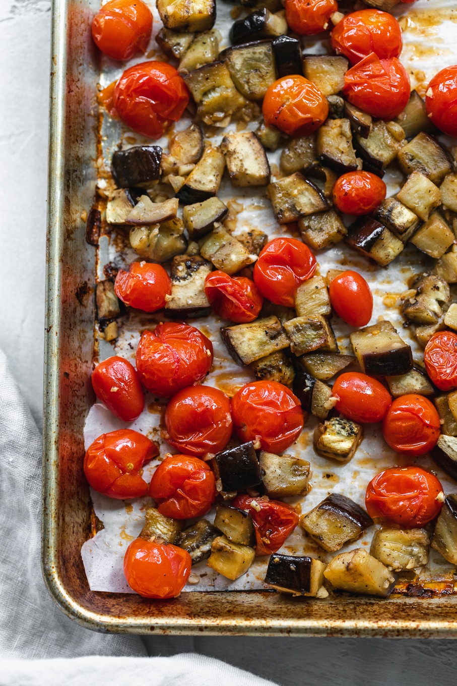 Overhead close up shot of a sheet pan filled with roasted tomatoes and eggplant