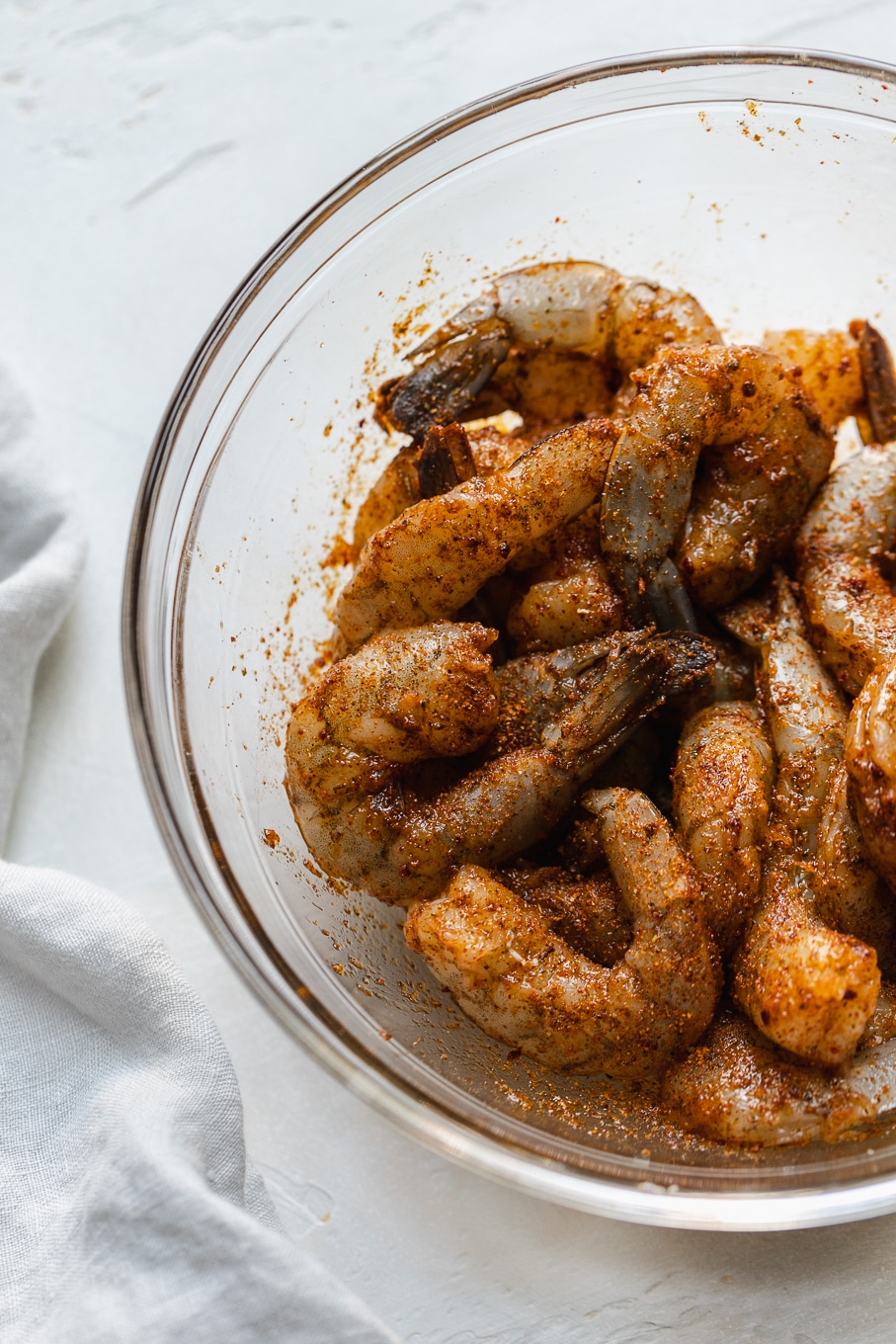 Overhead shot of a bowl of raw shrimp covered in cajun seasoning