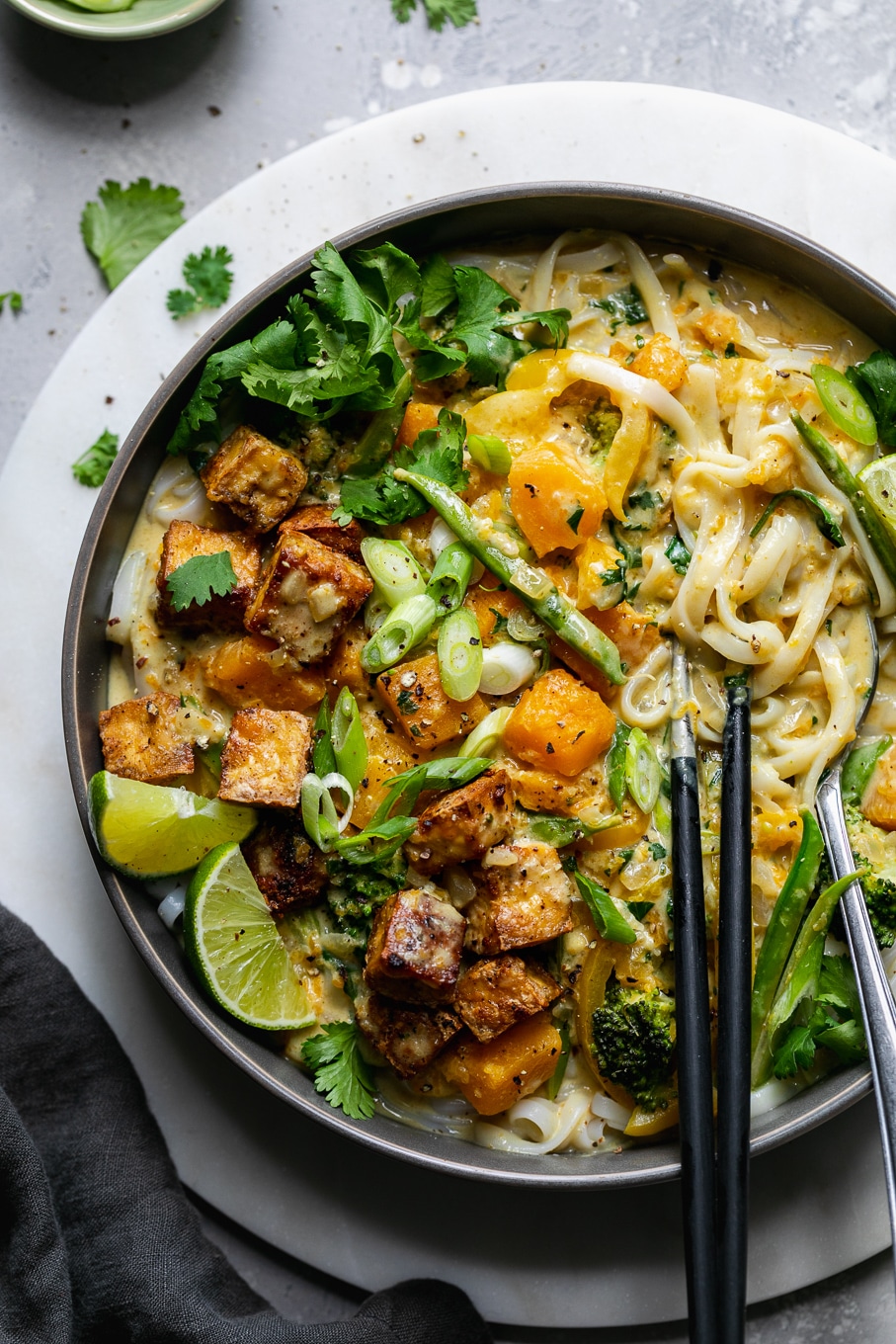 Overhead close up shot of a vibrant veggie filled noodle bowl with chopsticks and a fork
