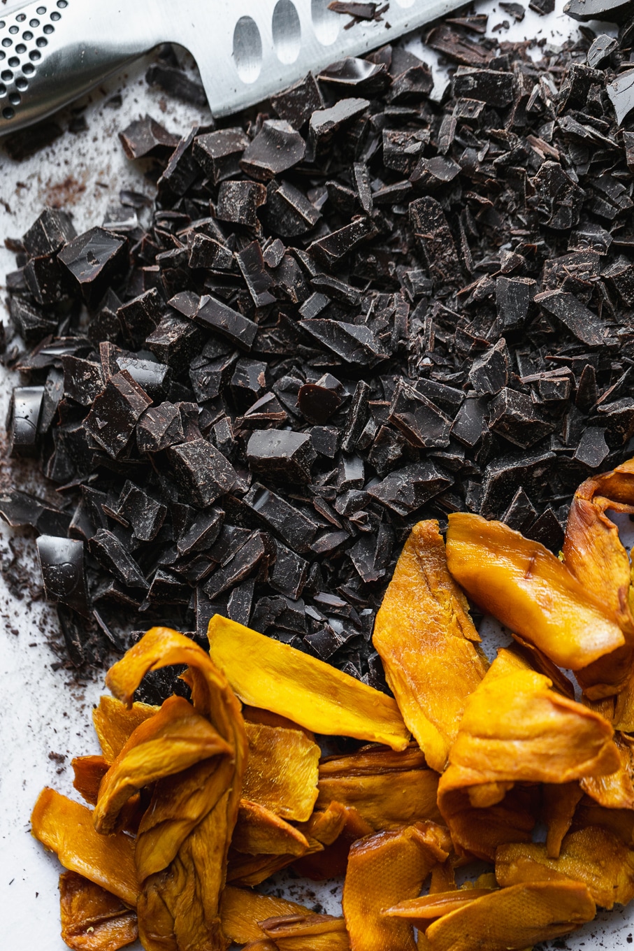 Overhead close up shot of chopped dark chocolate and dried mango