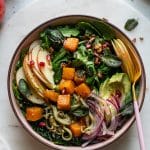 Overhead shot of a colorful fall salad with a pink and gold fork resting in the bowl