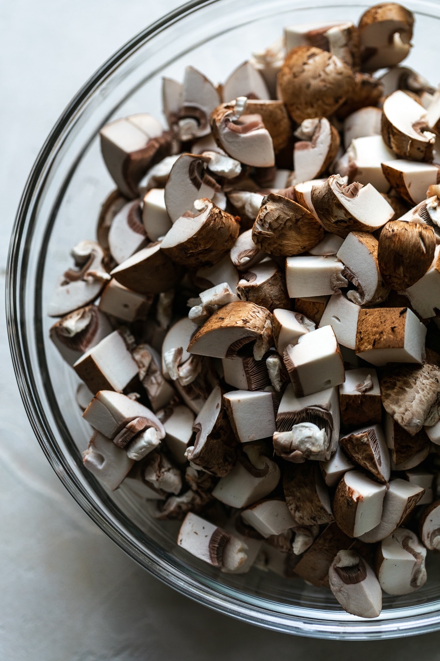 Overhead close up shot of a bowl filled with chopped fresh mushrooms