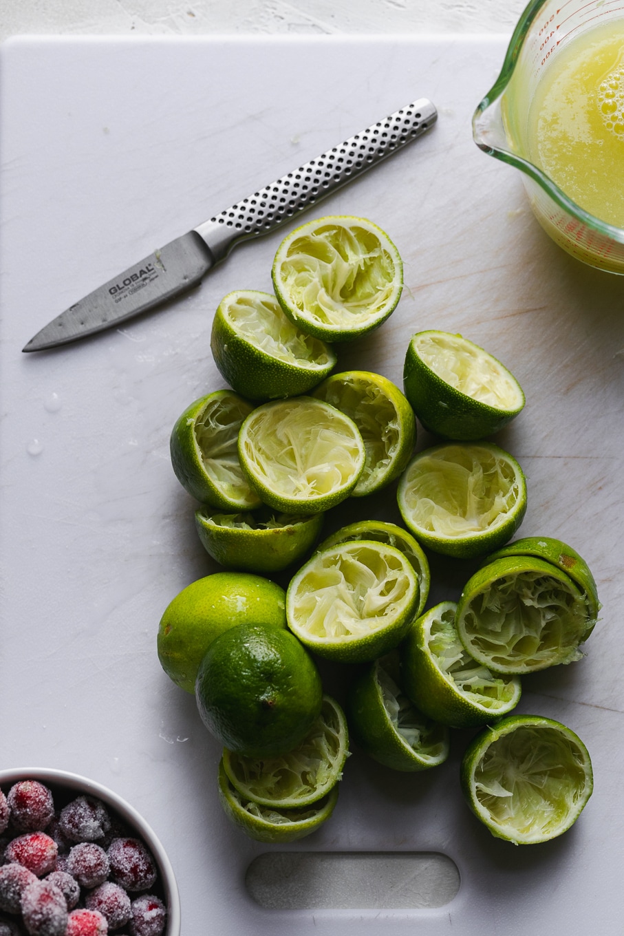 Overhead shot of juiced limes on a cutting board with a knife