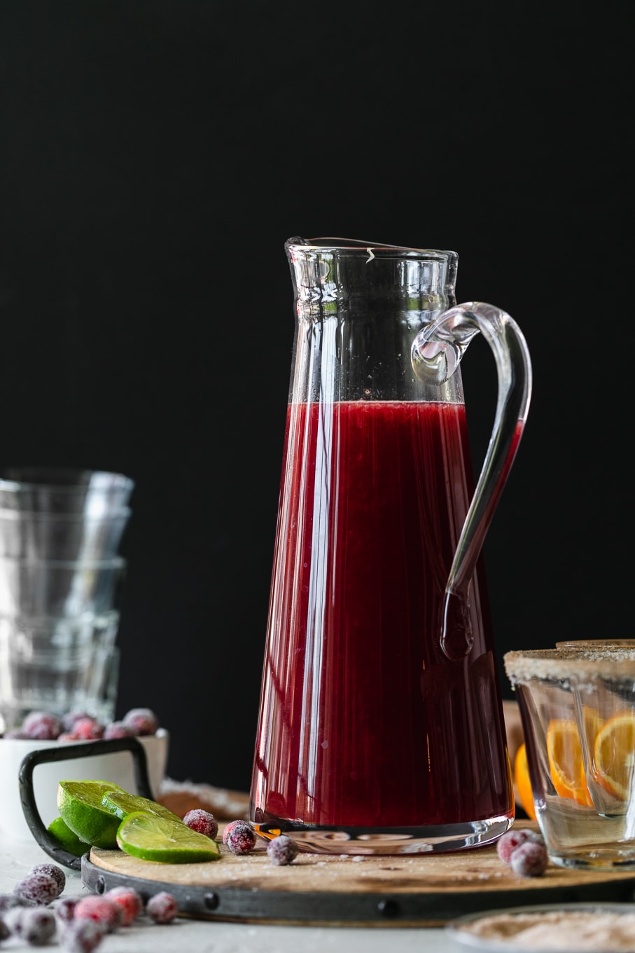 Straight on shot of a pitcher of cranberry margaritas against a black background