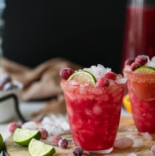 Shot of a cranberry margarita tarnished with lime and sugared cranberries
